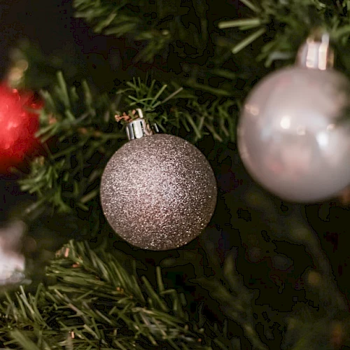 The image shows a Christmas tree decorated with red, silver, and glittery silver ornaments.