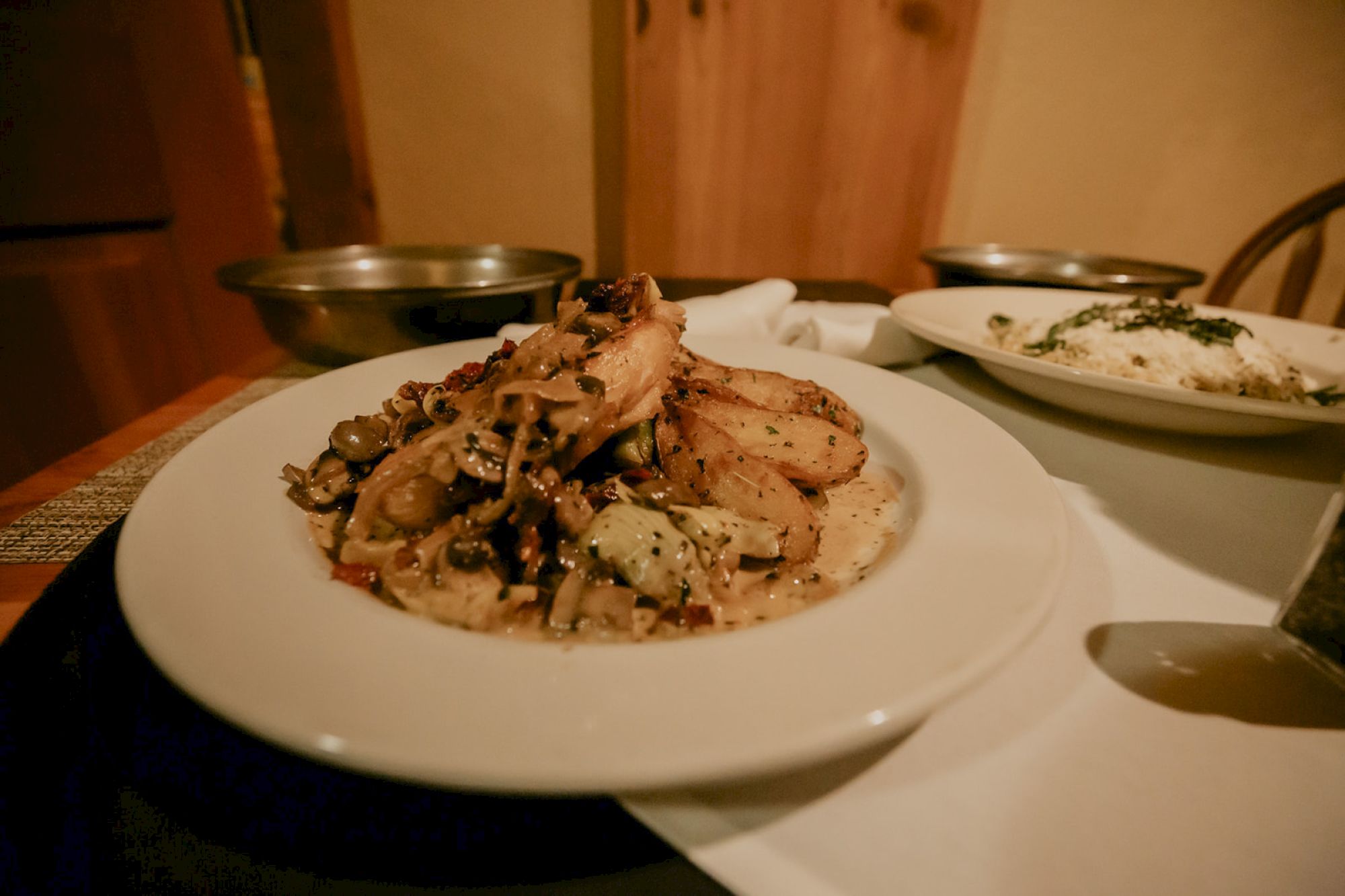 The image shows a plate of chicken with a creamy mushroom sauce and roasted potatoes, alongside another plate with rice.