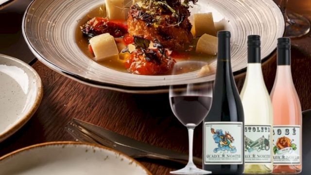 A fine dining scene with a plated main dish, several wine glasses, and bottles on a table, suggesting a sophisticated dinner with wine pairings.